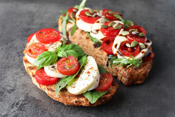 Delicious sandwiches with mozzarella cheese and tomatoes on grey table, closeup