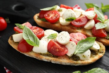 Delicious sandwiches with mozzarella cheese, tomatoes and basil on dark table, closeup