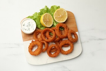 Fried squid rings served with sauce on white marble table, top view