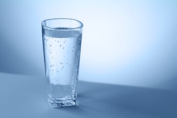 Refreshing soda water in glass on table against light blue gradient background, closeup. Space for text