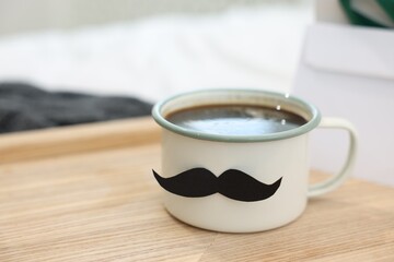 Happy Father's Day. Cup with mustache on bed at home, closeup. Space for text