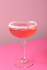 Martini cocktail with sugar in glass on pink background, closeup