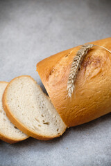 A freshly sliced sourdough bread on a table with ear of wheat