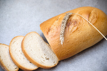 A freshly sliced sourdough bread on a table with ear of wheat