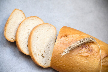 A freshly sliced sourdough bread on a table with ear of wheat