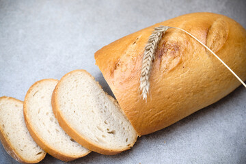 A freshly sliced sourdough bread on a table with ear of wheat