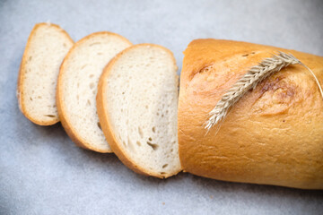A freshly sliced sourdough bread on a table with ear of wheat