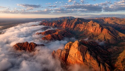 Aerial view of dramatic red rock formations rising above a sea of clouds at sunrise