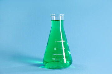 Conical flask with green liquid on light blue background