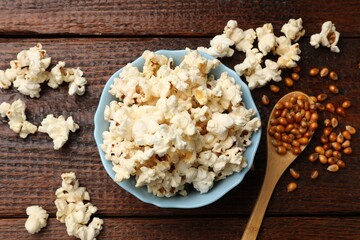 Tasty popcorn and corn kernels on wooden table, flat lay