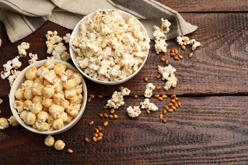 Tasty popcorn and corn kernels on wooden table, flat lay. Space for text