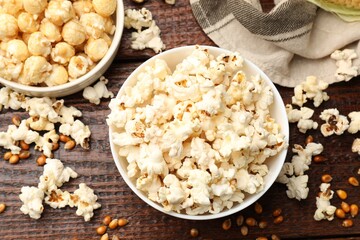 Tasty popcorn and corn kernels on wooden table, flat lay