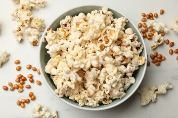 Tasty popcorn and corn kernels on white marble table, flat lay