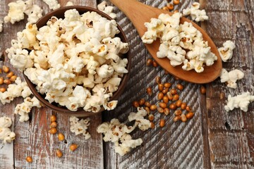 Tasty popcorn and corn kernels on wooden table, flat lay
