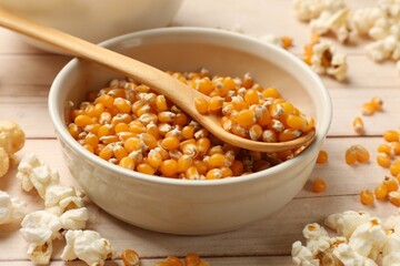 Corn kernels and tasty popcorn on white wooden table, closeup