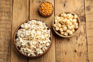 Tasty popcorn and corn kernels on wooden table, flat lay