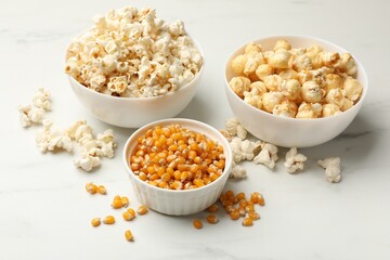 Tasty popcorn and corn kernels on white table, closeup