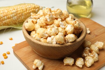 Tasty popcorn and corn kernels on white table, closeup
