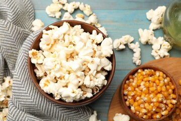 Tasty popcorn and corn kernels on blue wooden table, flat lay