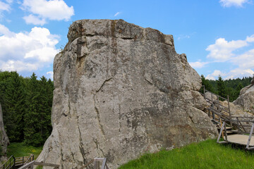 ​A powerful, majestic rock emerging from the ground dominates the landscape, its surface covered in unique textures.