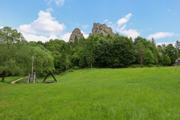 Majestic rocks rise above a picturesque mountain valley, covered with the lush greenery of forest and grass. The tranquil landscape creates a perfect sense of harmony with nature and beckons you to tr