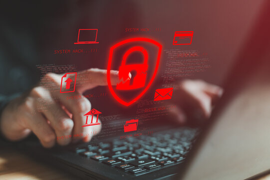 Hacker hands typing on laptop with red glowing security shield and system hack alerts. Cybersecurity breach concept showing unauthorized access, data theft and malicious cyber attack in progress.