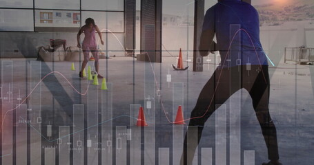 Navigating neon cones, pair wearing sportswear making moves inside warehouse gym with data overlay