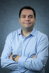 Friendly businessman with crossed arms, wearing blue shirt, looking at camera. Perfect for corporate, career planning, office work, manager or CEO. Studio portrait with copy space.