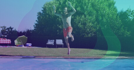 Jumping man in red swim trunks splashing into backyard pool, with picnic table, umbrella and cooler