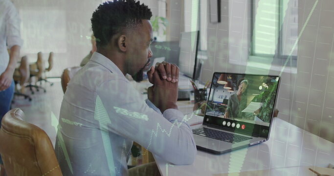 Leaning man wearing button-up shirt and dark pants focusing on laptop at open office, with plant