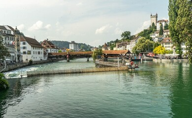 Panoramic photo of Lucerne from the Reuss River perspective, featuring the wooden Spreuer Bridge and the old tower, an element of the city's fortifications.