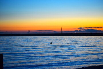 Sunset over the sea with silhouettes of buildings and trees