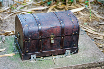 Vintage wooden treasure chest chained to a concrete base in a garden