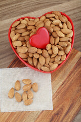 Fresh almonds in heart shape bowl