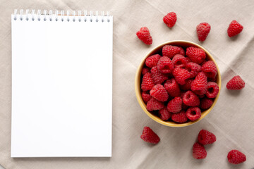 Organic Raw Red Raspberries in a Bowl, blank notepad, top view.