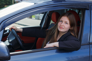 A beautiful happy woman is driving a car. Renting and selling cars.