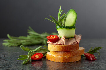 Bread slices with pate, cucumber, red pepper, and rosemary.