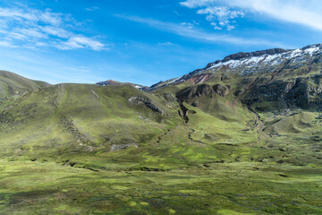 Fototapeta premium Lush green landscape of the Andes with snow capped peaks under a brilliant blue sky at Palcoyo Trek in Peru