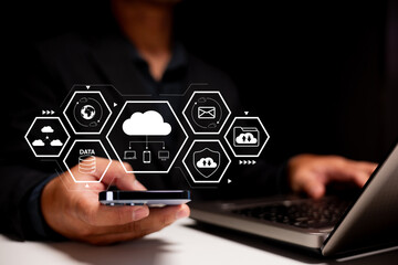 Cloud storage and data management. A businessman uses smartphone and laptop in a modern office to synchronize files, secure data, and access global cloud services for smart digital workflow.