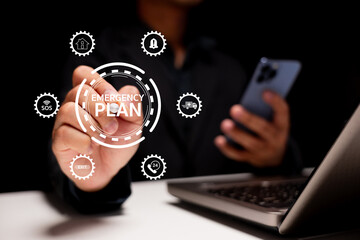 Emergency plan and crisis management. A businessman uses smartphone and laptop in a modern office while interacting with digital icons for safety, SOS, evacuation, and disaster recovery planning.