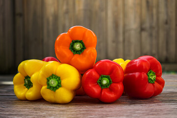 Close-up of fresh orange, yellow and red bell peppers on wooden table