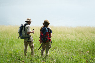 Hiking Couple Walking Near Lakeside with Backpacks and Trekking Poles, Summer Travel Journey in Wilderness, Sharing Outdoor Adventure and Relaxation