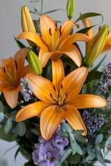 Fototapeta premium Vibrant orange lilies and lavender blooms in a floral arrangement