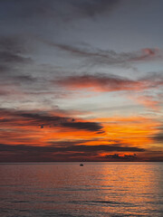 Beautiful tropical sunset over the sea with colorful sky, clouds and sun reflection on the water. Scenic evening view at Koh Phangan island, Thailand. Perfect vacation and travel background.