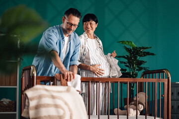 Happy couple preparing baby crib in modern nursery