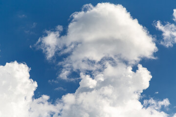 White cap of clouds in blue sky close-up, cumulus white clouds in daylight sun, fluffy textured clouds in the sky with interplay of shadow and light