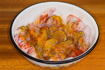 Raw chicken wings sprinkled with different spices for following grilling