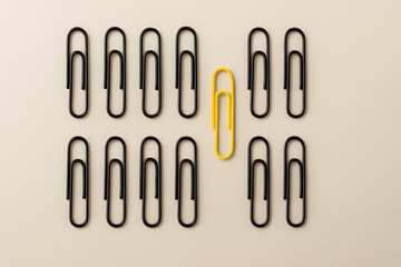 Yellow paperclip standing out among black paperclips concept individuality leadership difference unique idea contrast innovation creativity business teamwork diversity organization distinct standout s