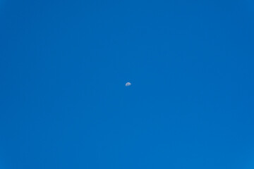 Blue sky with visible moon in daylight
