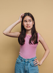 Obraz premium Young woman expresses confusion while standing against a solid colored background in casual attire